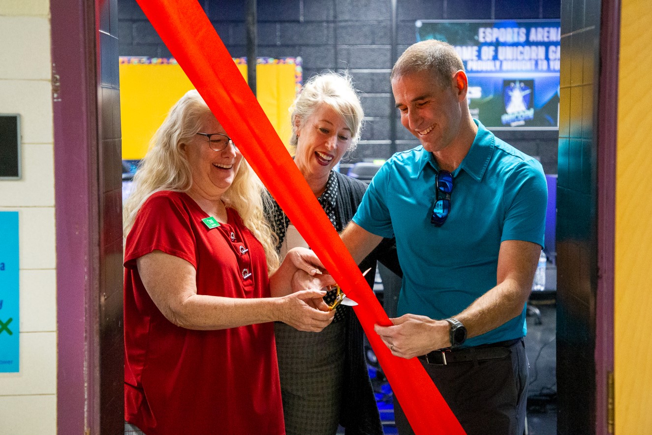 Staff smile as they cut the ribbon for the new eSports lab.