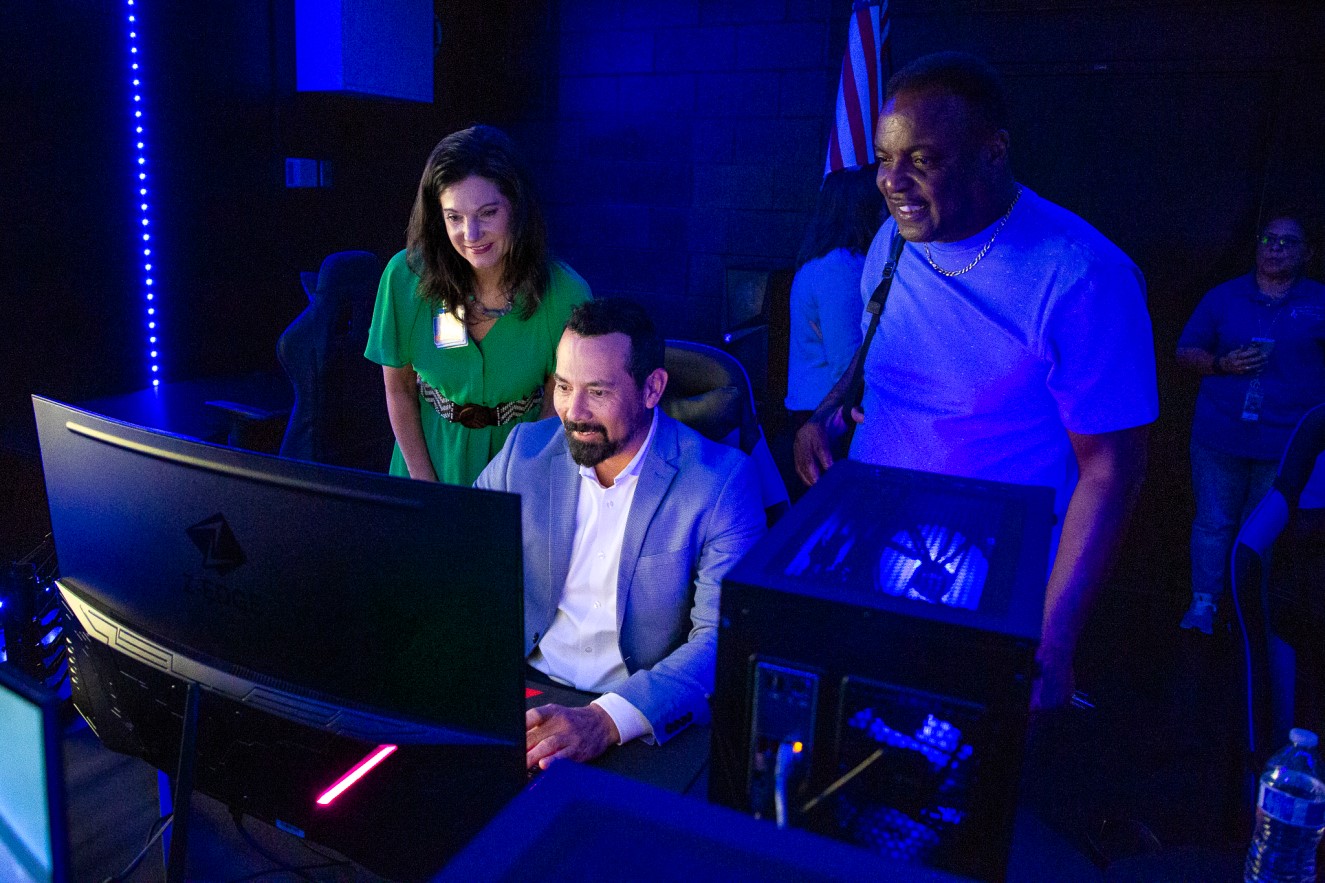 Staff members smile while looking at one of the new computers