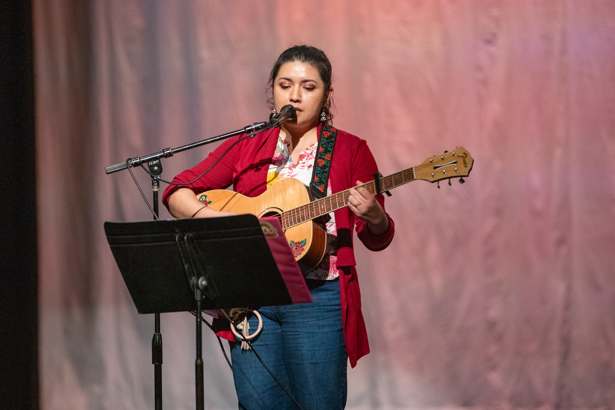 A girl in a red sweater plays guitar and sings