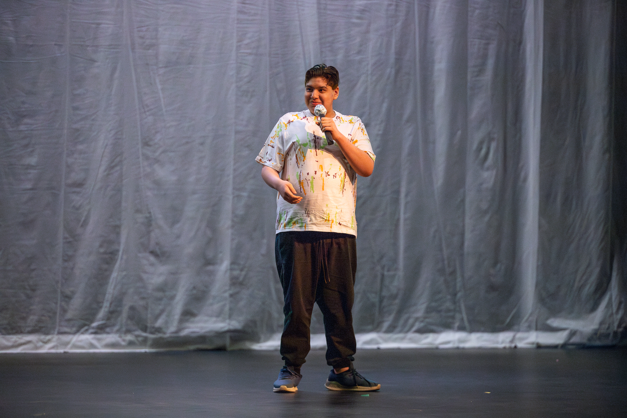 A boy in a tie-dye shirt performs with a mic