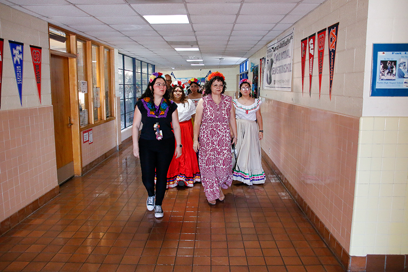 Staff lead students down the hallway in a procession