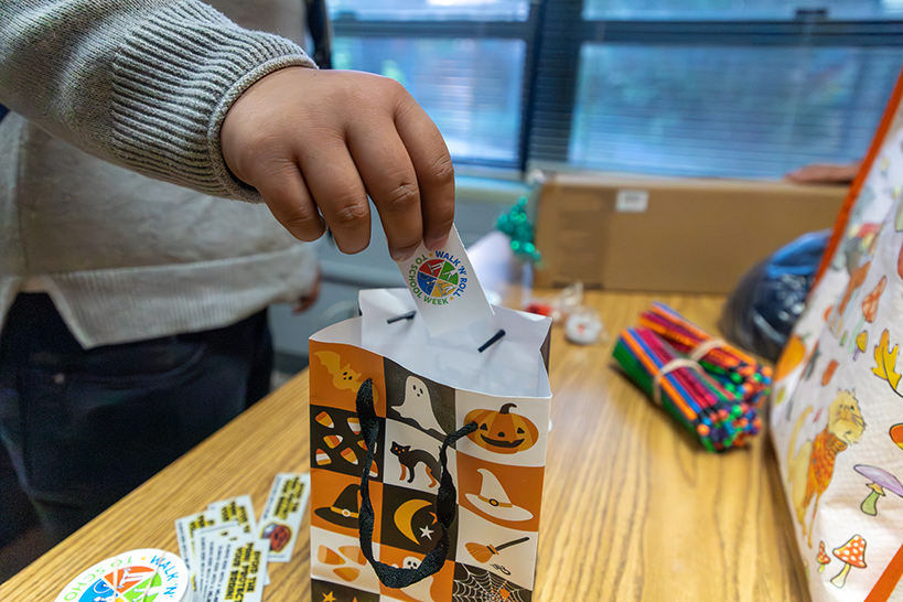 A boy pulls a small piece of paper out of a Halloween gift bag
