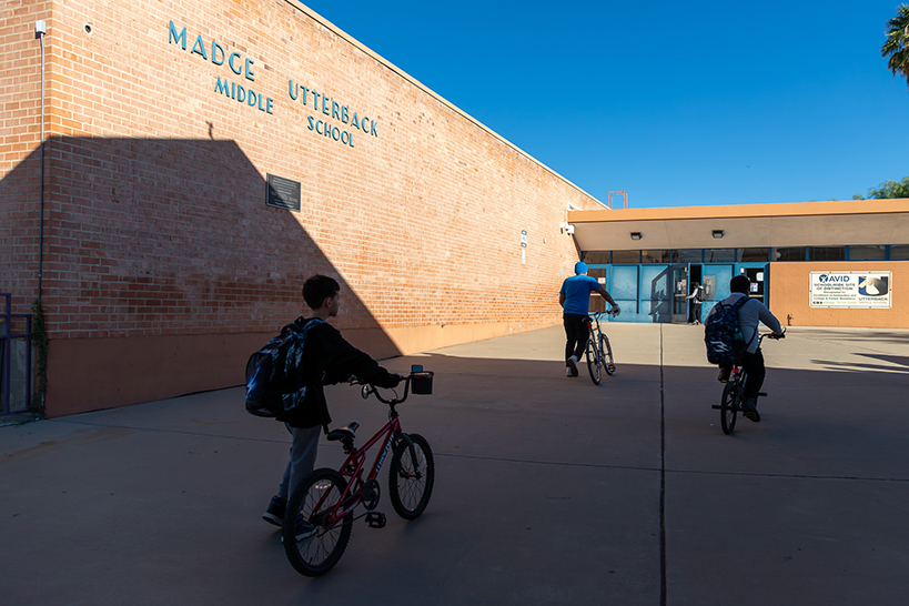 A boy and man push their bikes in front of the school