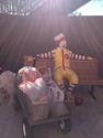 A Ronald McDonald bench with all of the toys next to him in a wagon.